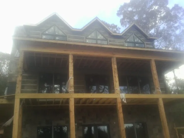 Dormers and porch framing on a large log home under construction — Roof Coating work by our crew in Prudence Island