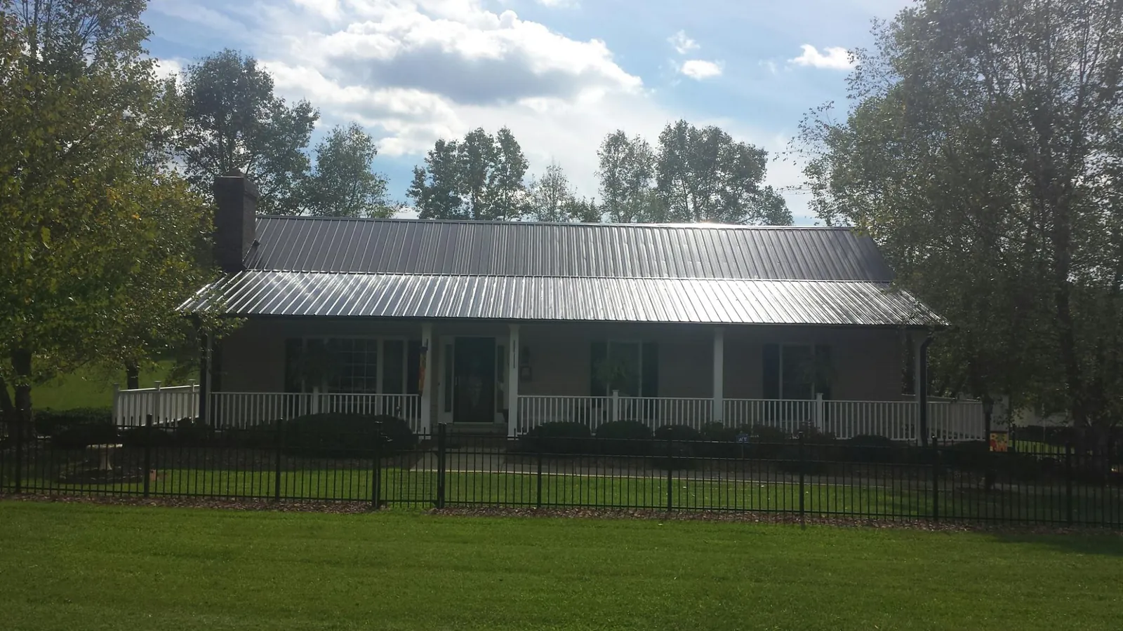 Gray metal roof on a brick ranch with a full width front porch — Gutter Guard Installation work by our crew in Prudence Island