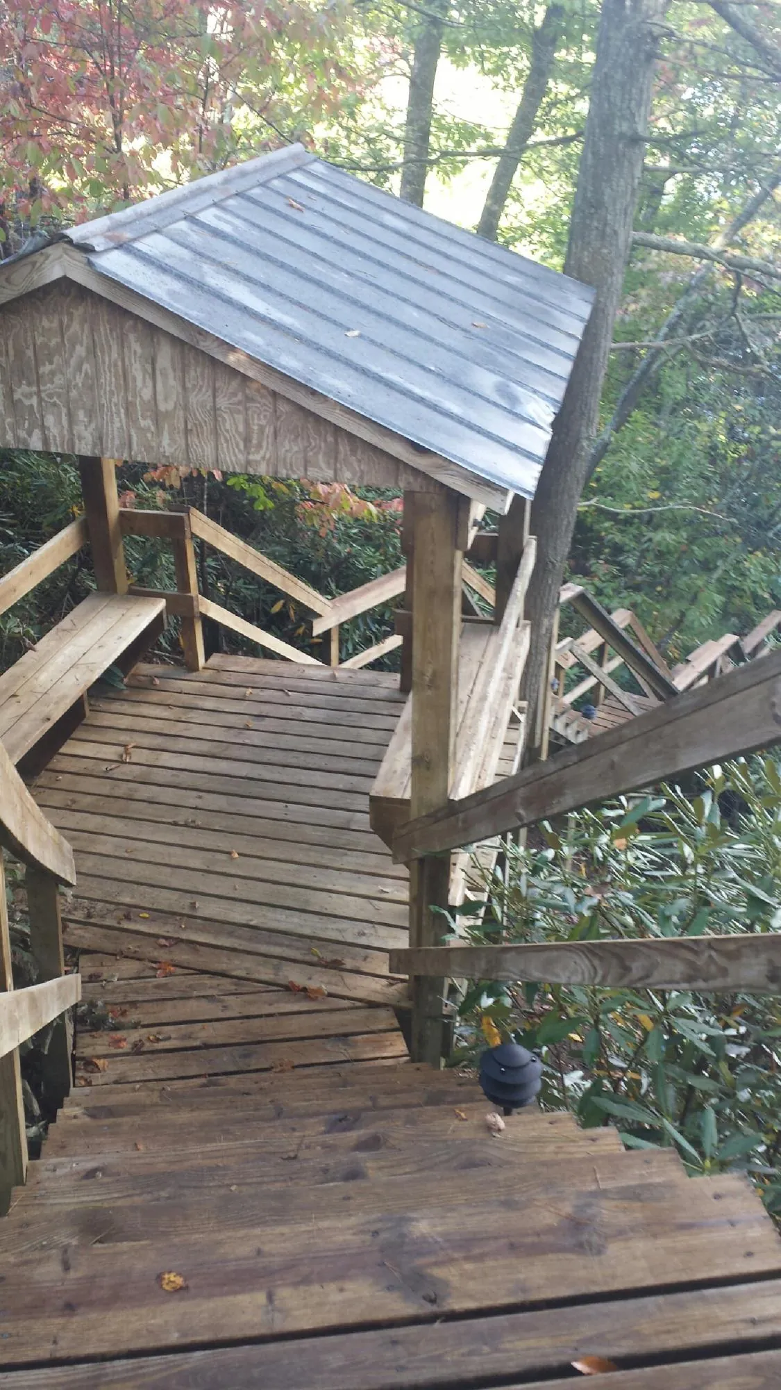Metal roofed shelter over wooden steps on a wooded walkway — Skylight Repair & Installation work by our crew in Prudence Island