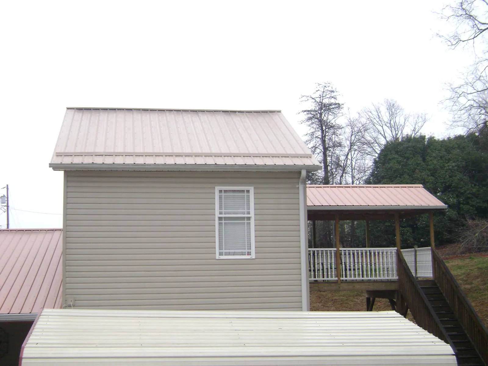 Tan metal roofs on a two story addition and attached porch, from a Roof Replacement job in Prudence Island