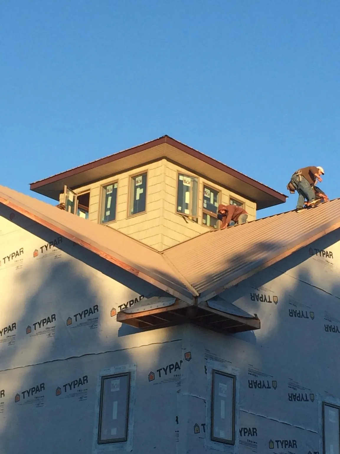 Roofers working around a rooftop cupola on a new metal roof at sunset — Roof Waterproofing in Prudence Island by Roofing Brothers